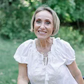 Kasia outslide leaning on a fence while smiling at the camera