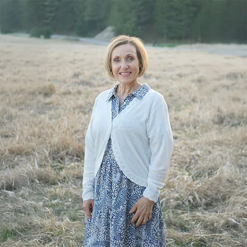 Kasia standing in a field in a blue dress and white sweater