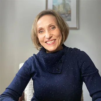 Kasia in blue sweater sitting in white chair