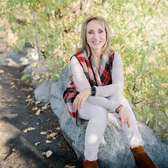 Kasia in white blouse outside with green foliage in the background