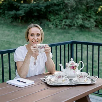 Kasia sitting at a table outside sipping tea